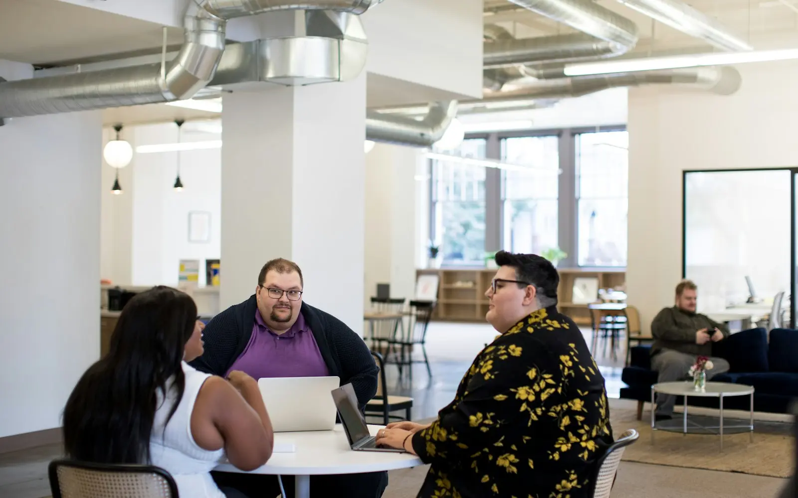 Three colleagues meeting at a table in a bright open-plan office