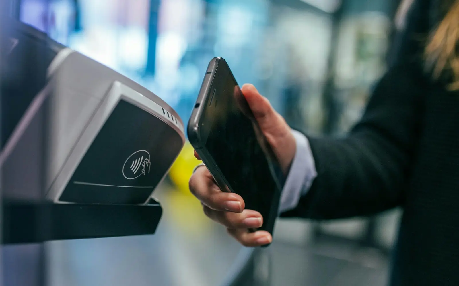 Hand holding a phone against a contactless card reader